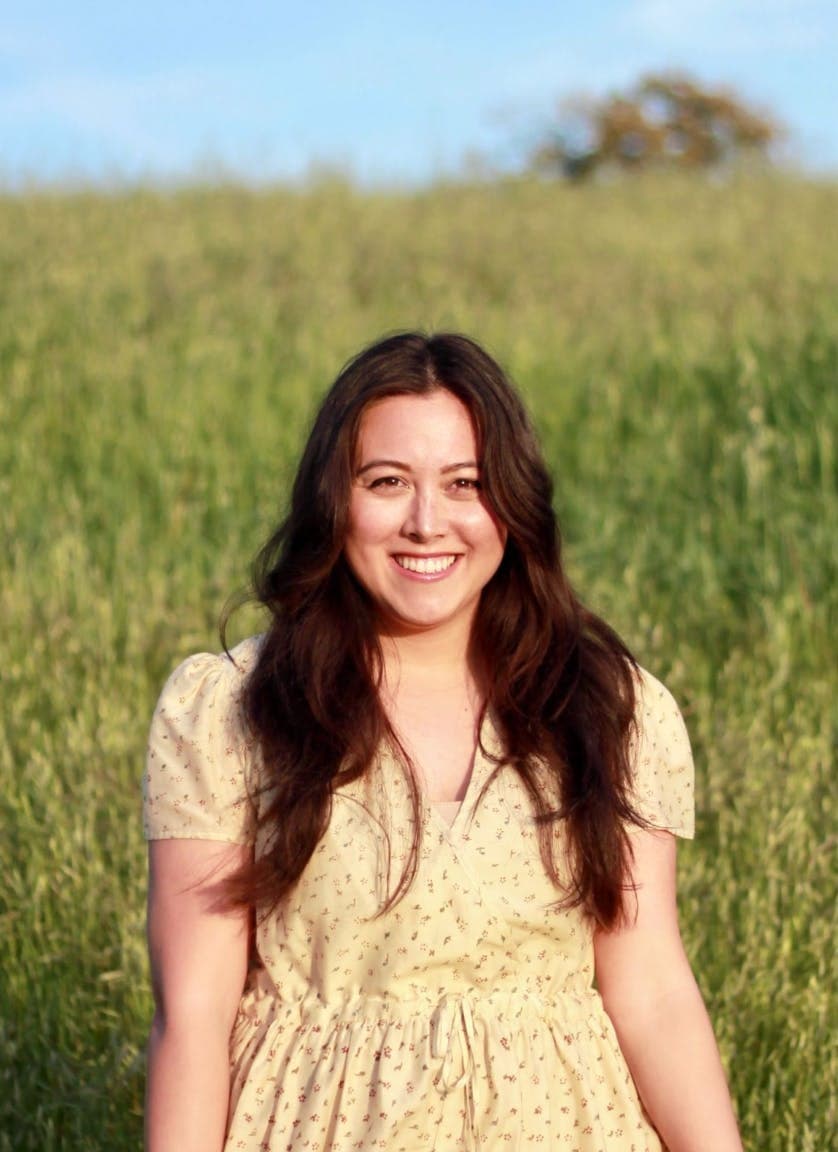Caitlin Blair - author in yellow dress in green field.